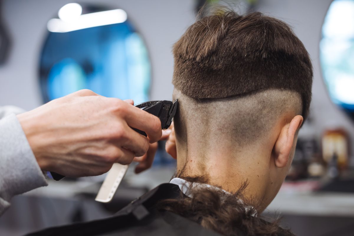 Férfi frizurákat vágó fodrász hajvágó géppel.