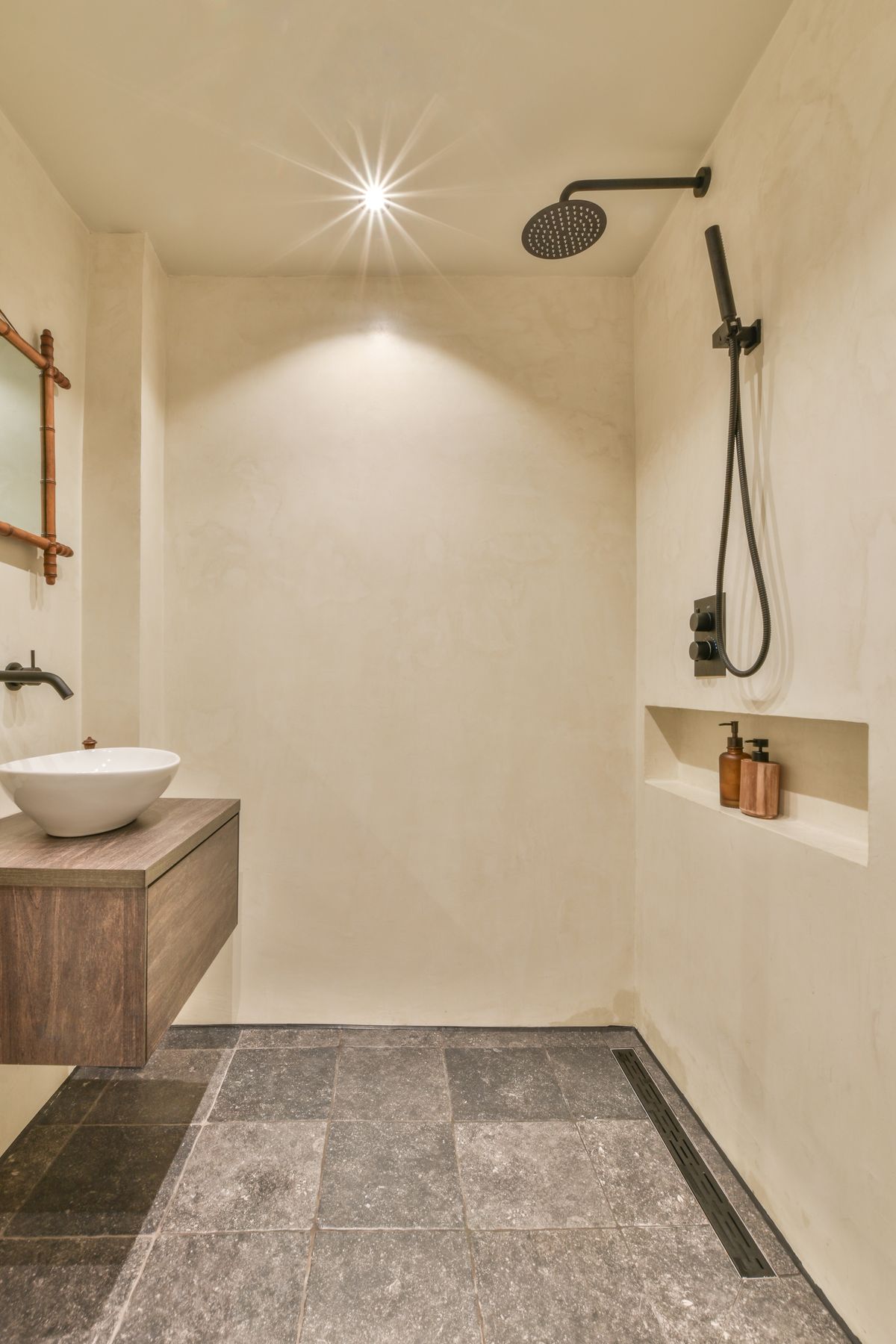 Black wall hung toilet in minimalist interior of bathroom with flowers on shelf above