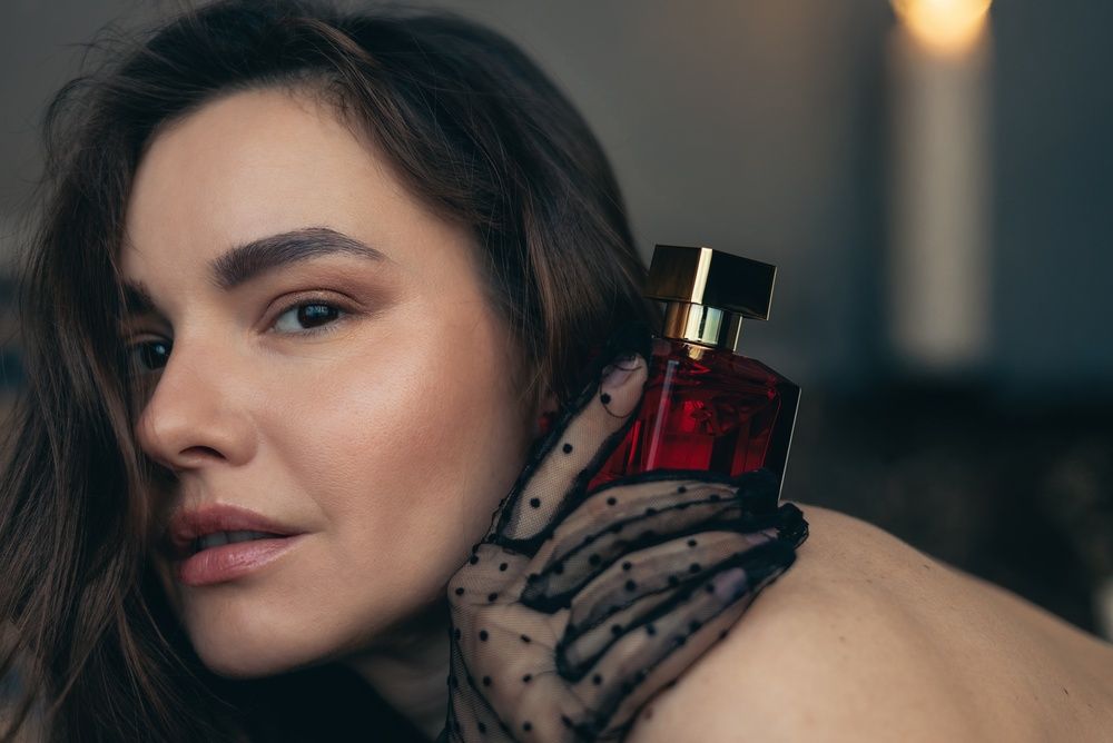 Szép nő kezében parfüm.