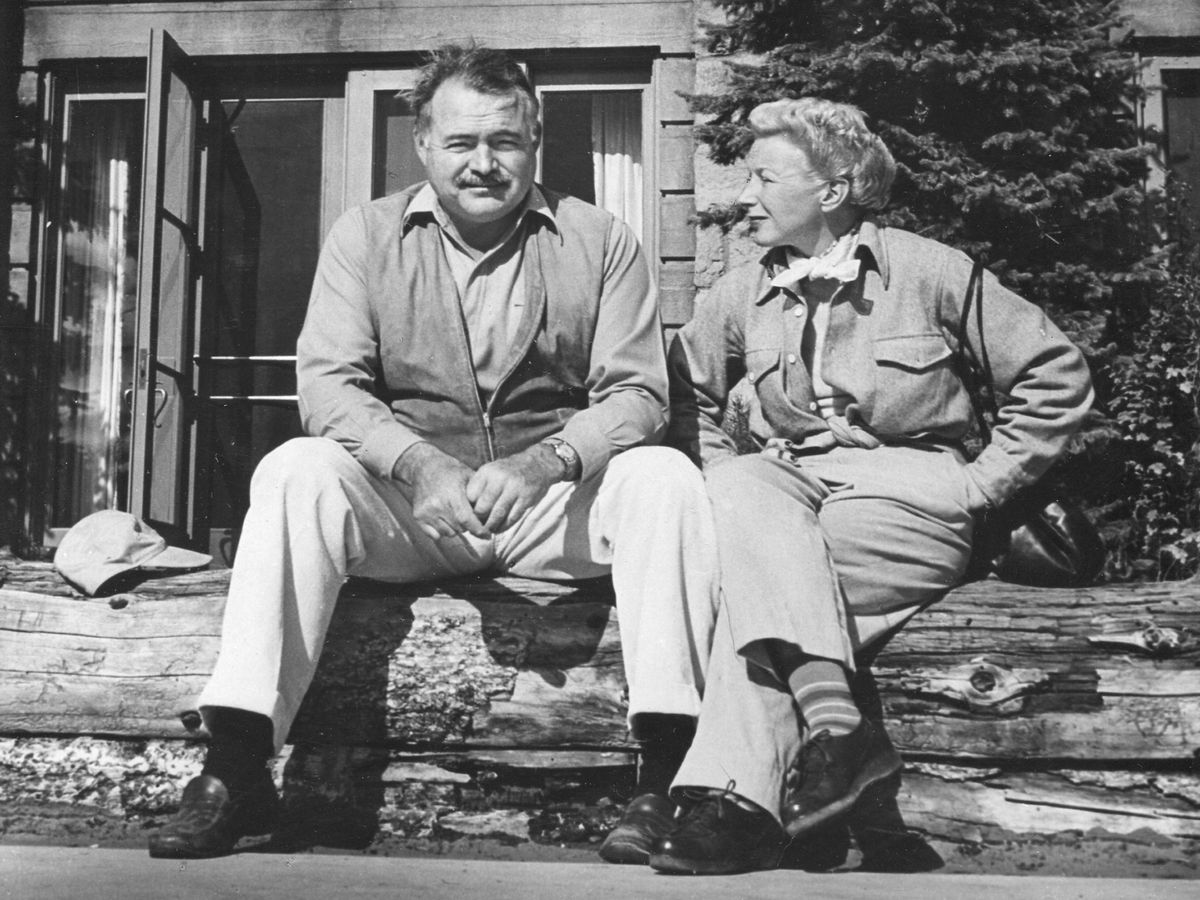 Portrait of American author Ernest Hemingway (1899 - 1961) and his wife, journalist Mary Welsh Hemingway (1908 - 1986), as they sit outside on a log fence while on vacation, 1946. (Photo by PhotoQuest/Getty Images)