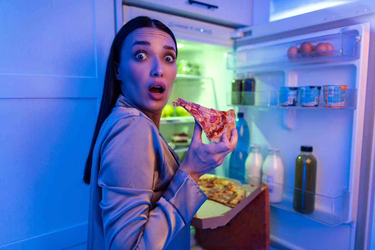 Egy nő, akit rajtakaptak a hűtő előtt az éjféli nassoláson. Fogyás szempontjából nem jó omen az éjféli kajálás.