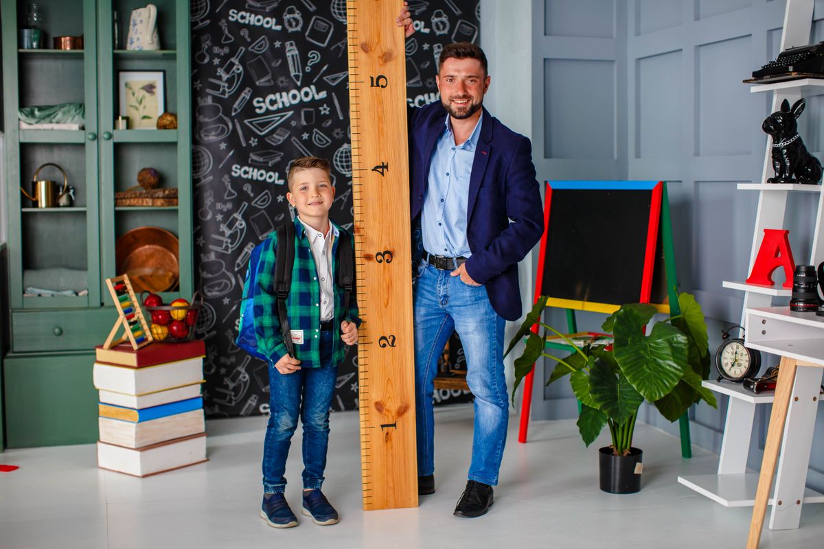 menő apatípusba tartozó, laza apuka, mellette egy vonalzóval és a fiával