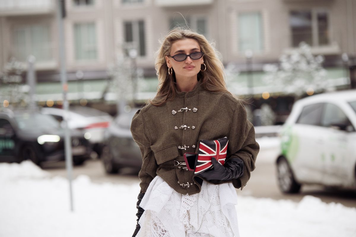 Fiatal modell női kiegészítőkkel a kezében sétál az utcán 