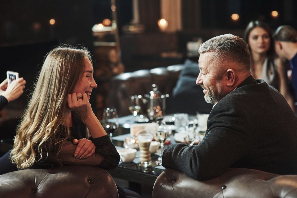 Generációs különbségek: egy fiatal nő egy idősebb férfival randin egy étteremben. 