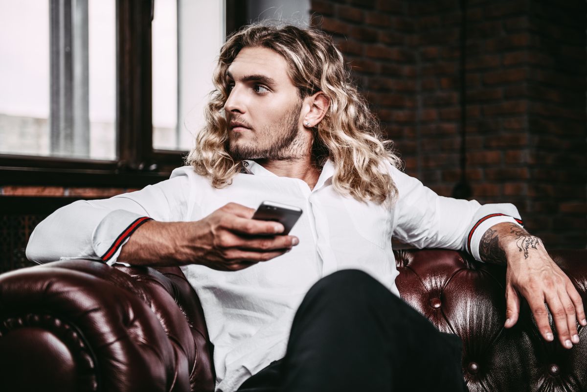 Young handsome man on his smartphone. Male beauty, fashion. Business style. Modern technologies.