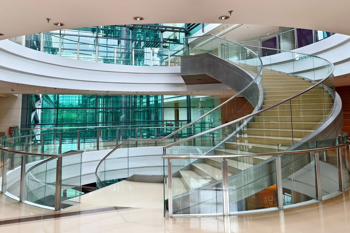 A modern, üvegkorlátos íves lépcső – a csendes, tudatos erő.