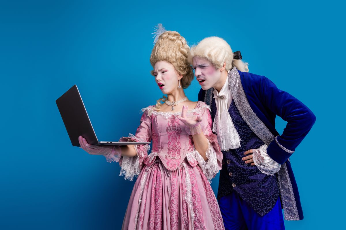 Egy viktoránus ruhába öltözött párocska lesi a laptopon, hogy mi az a Bridgerton stílusú storybooking trend.