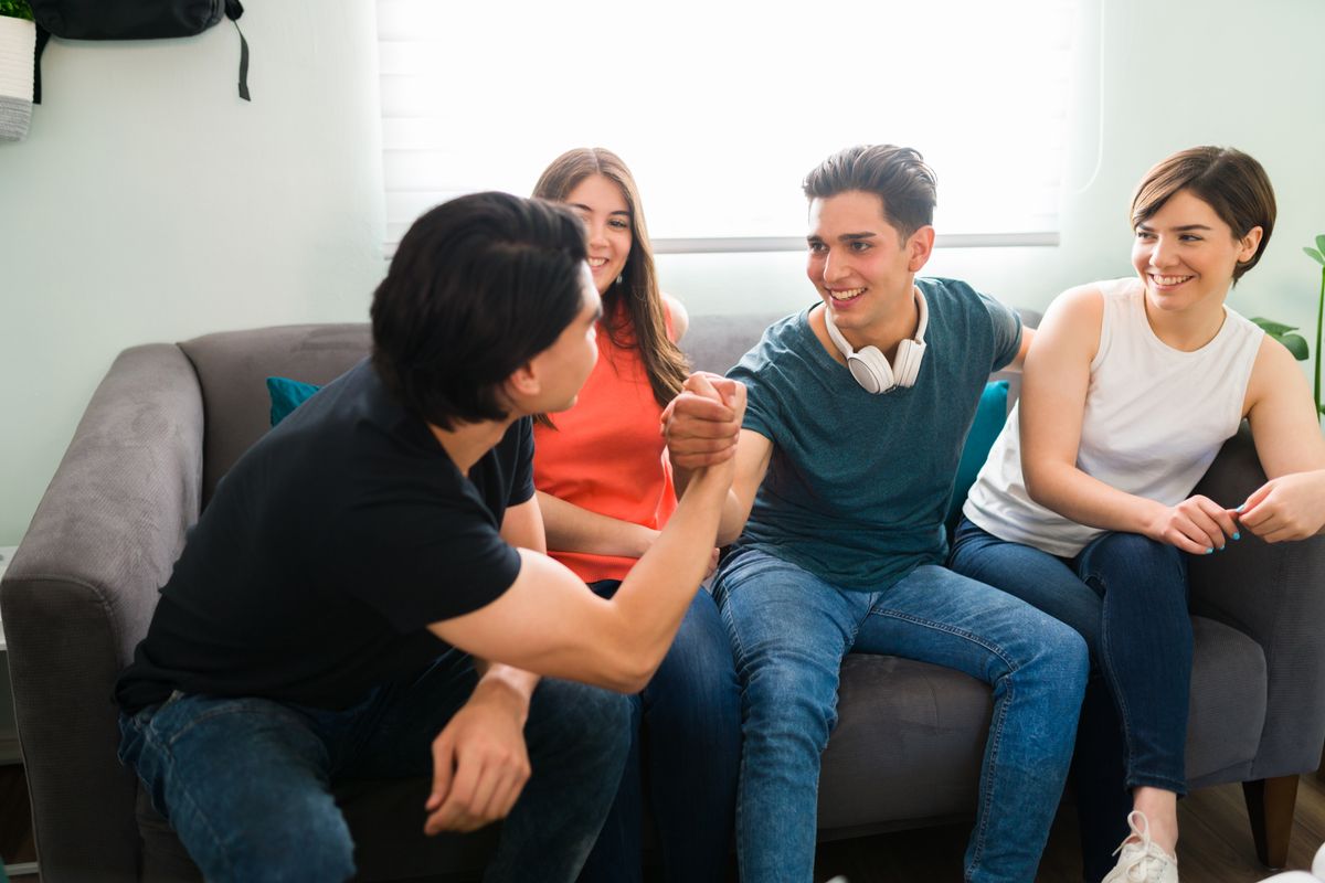 Egy baráti társaság a kanapén ülve élősködő barátokkal a köreikben nevetnek.