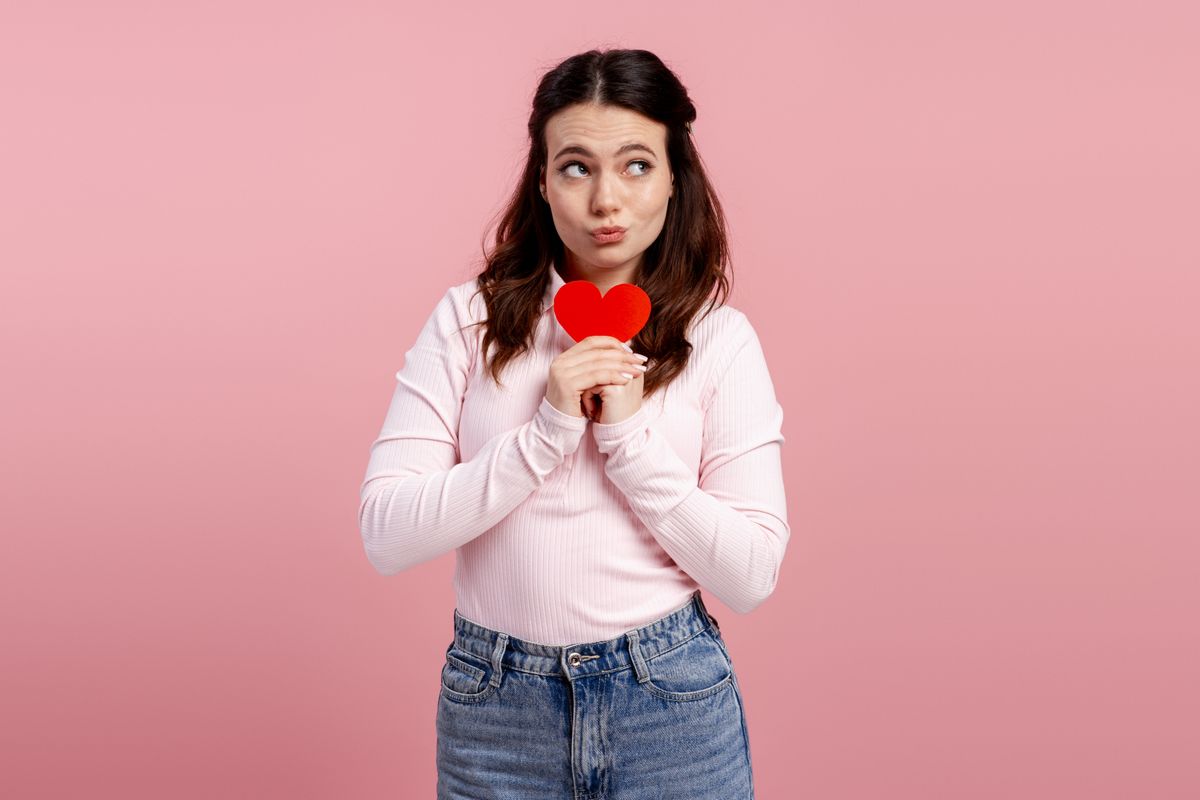 Kezdődő szerelem hatásai - egy fiatal, barna hajú lány papírszívet tart a kezében.