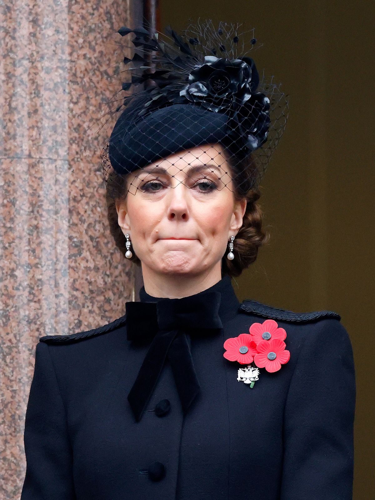 A képen Katalin hercegné összeszorított szájjal, feket kabátban. 