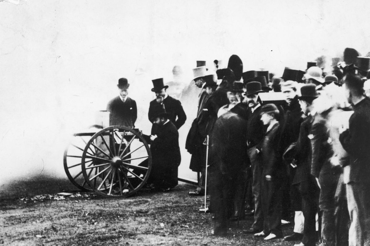 Hiram Maxim bemutatja korai géppuskáját, a walesi hercegnek, a későbbi VII. Edward királynak 1888-ban. A herceg kezeli a fegyvert, míg Maxim közvetlenül mögötte áll. 