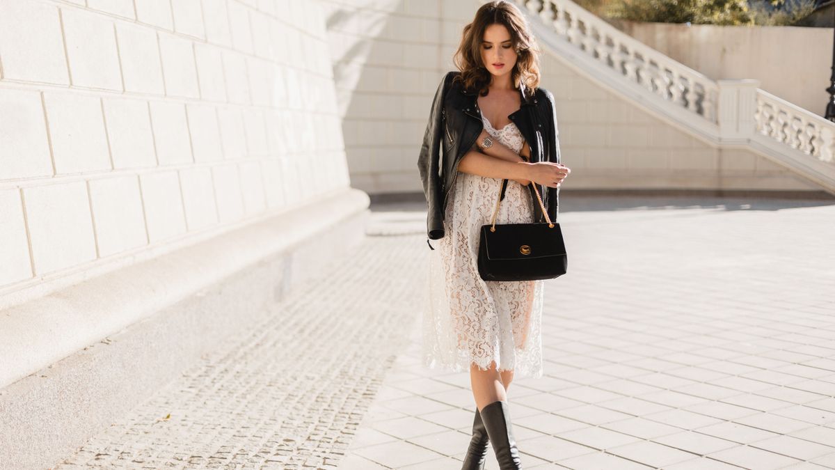 csipke, illusztrációképpen egy csinos modell fehér csipkeruhában és bőrdzsekiben pózol