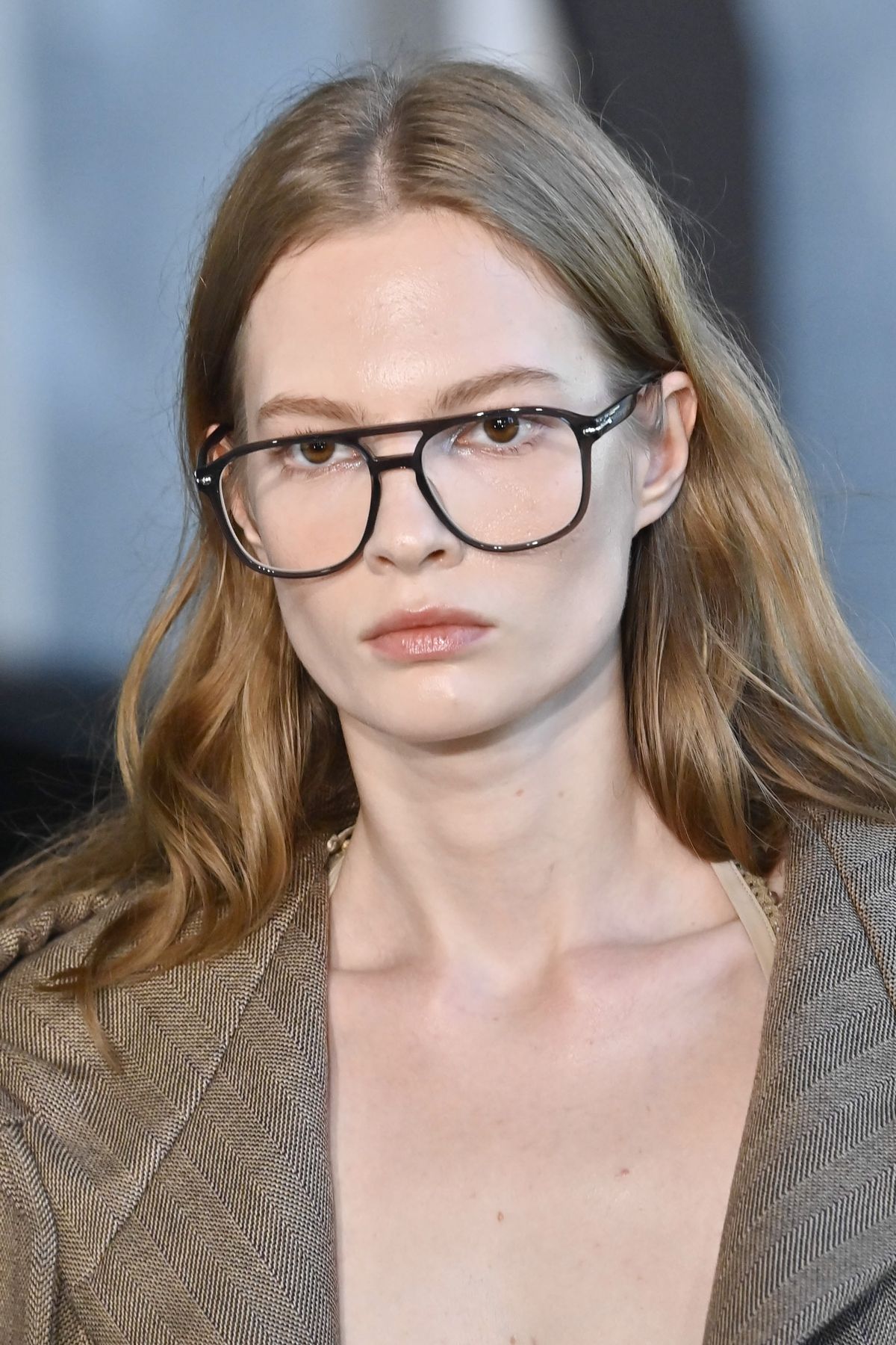 Szemövegsminktrükköt használó nő.