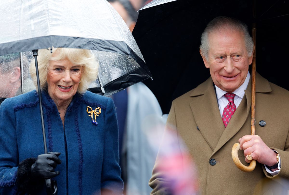 DEDHAM, ESSEX - FEBRUARY 05: (EMBARGOED FOR PUBLICATION IN UK NEWSPAPERS UNTIL 24 HOURS AFTER CREATE DATE AND TIME) Queen Camilla and King Charles III shelter under umbrellas as they meet members of the public during a walkabout after visiting The Sun Inn on February 5, 2026 in Dedham, Essex. (Photo by Max Mumby/Indigo/Getty Images)