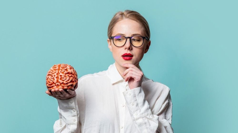Nő agyat tart a kezében. Fotó az intelligencia cikkhez. 