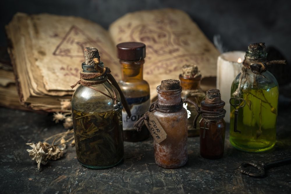Magic potions in bottles, ancient books and witchery herbs on wooden background, Halloween theme