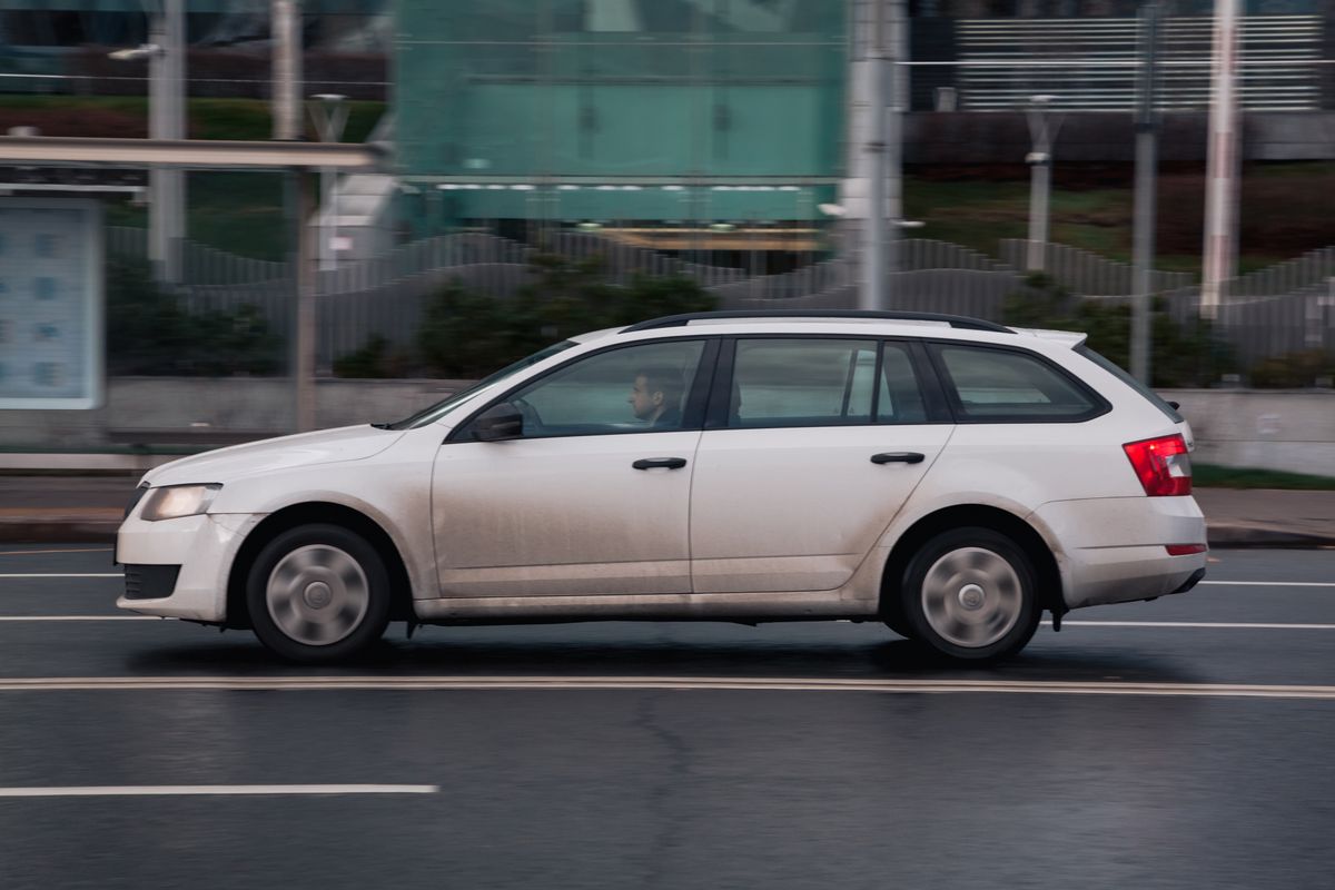 Moscow, Russia - October 2021: Fast moving Skoda Octavia estate on wet city road. White combi car rides on street. Used auto in fast motion with blurred background. speeding in the city concept