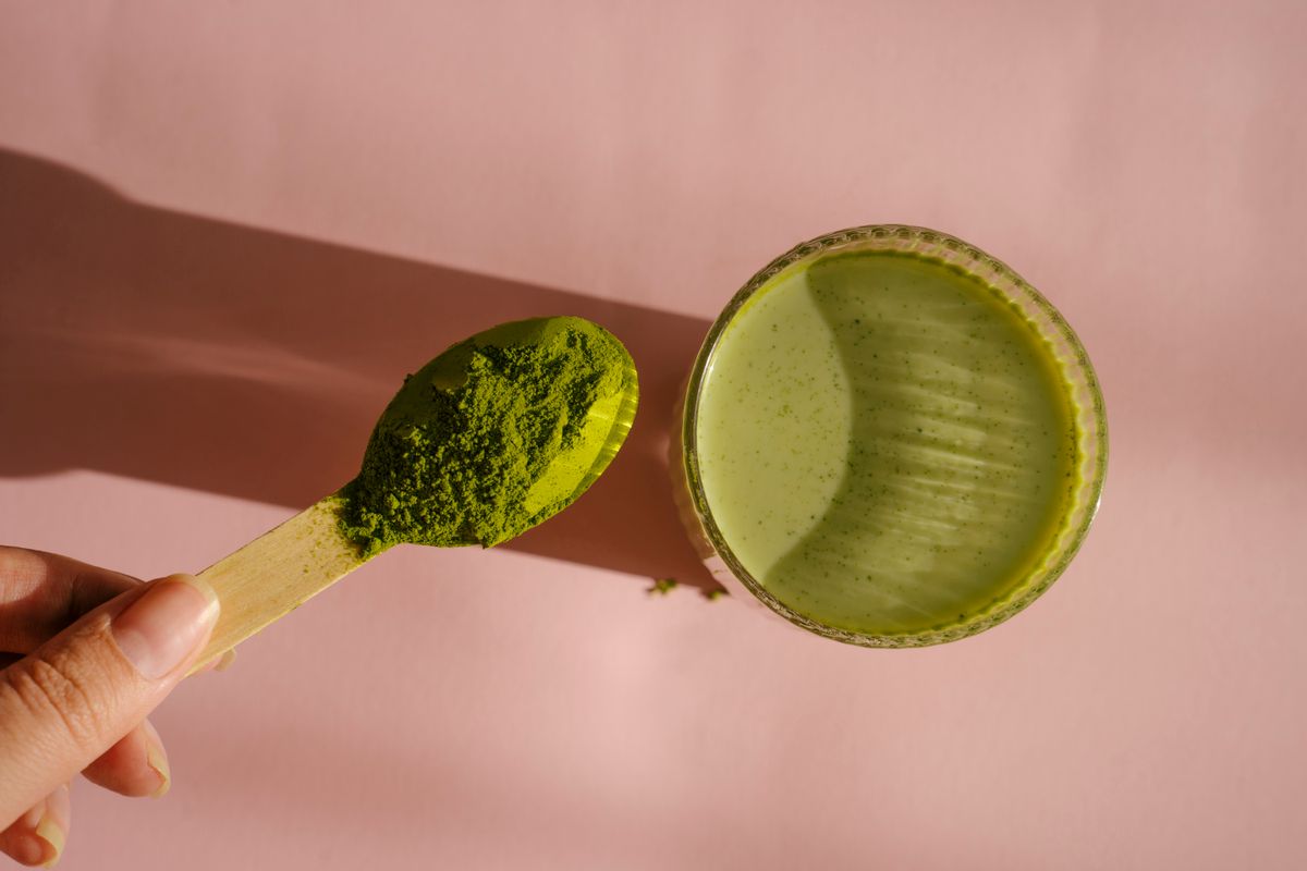 Glass of matcha on pink background. Matcha green tea powder in bright sunlight
