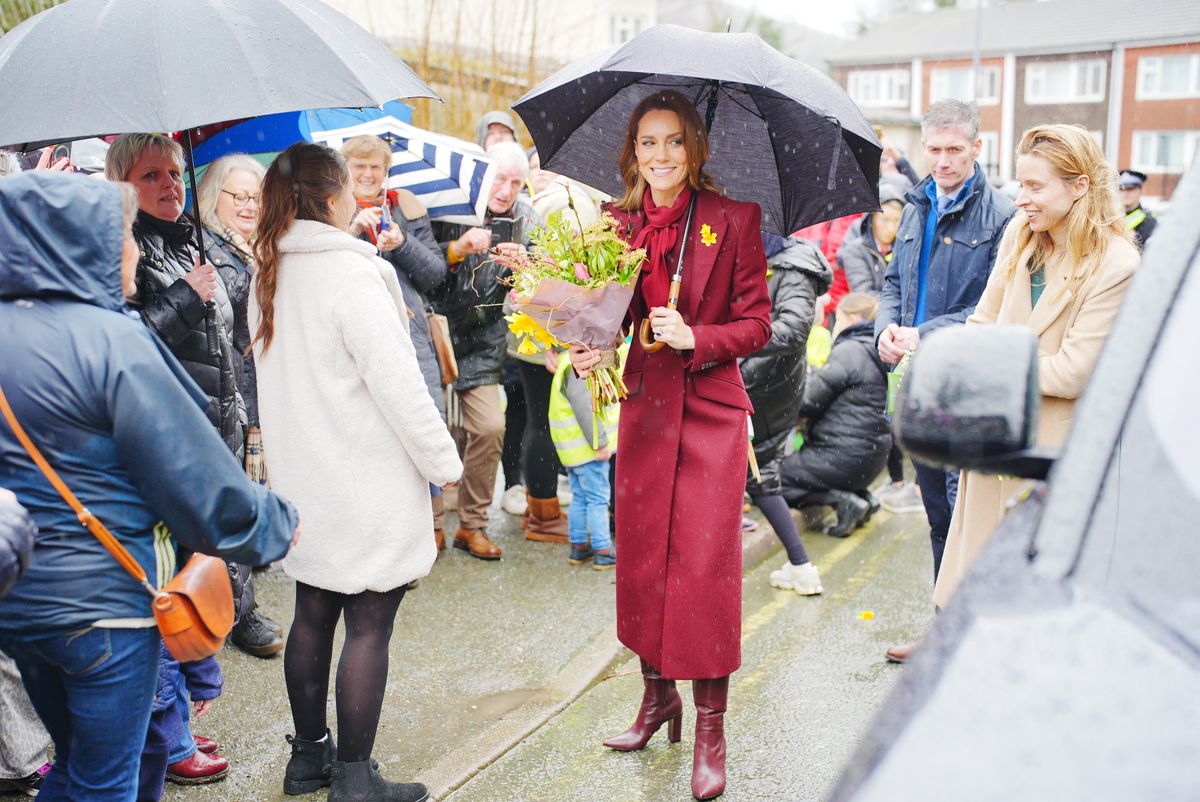 LLANIDLOES, UNITED KINGDOM - FEBRUARY 26: Catherine, Princess of Wales shelters from rain under a umbrella whilst meeting members of the public during a visit to the Hanging Gardens, a space dedicated to nurturing community resilience and creativity, on February 26, 2026 in Llanidloes, Wales. The Prince and Princes of Wales visited communities in Powys, Wales today ahead of St David's Day. (Photo by Ben Birchall - WPA Pool/Getty Images)