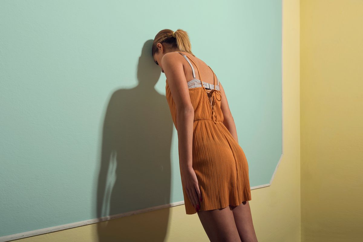 Egy szomorú nő fejével támasztja a falat, negatív gondolkodású emberek közé tartozik. 