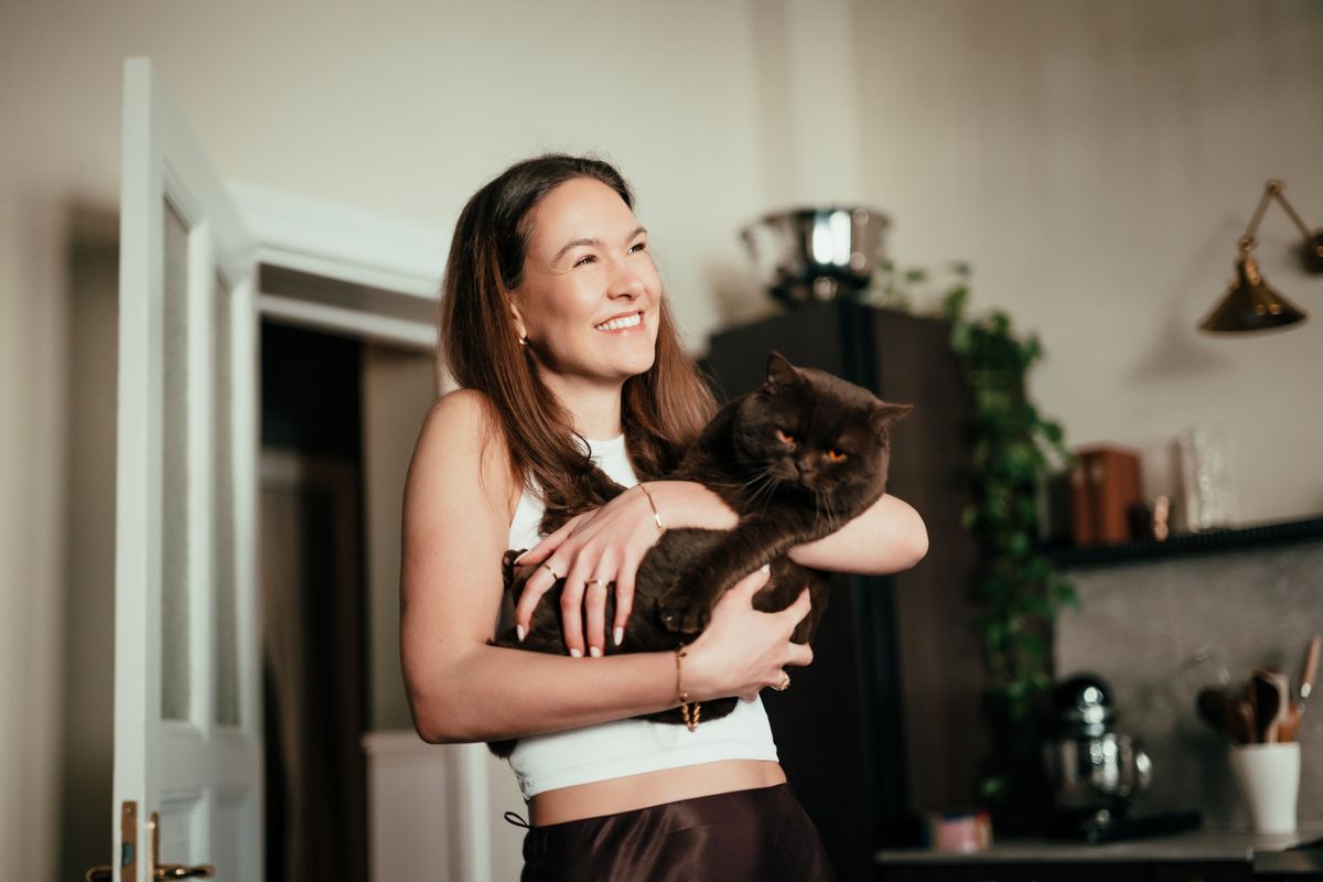 Egy nő egy szomorú, a kezében egy ideges fekete macska van.