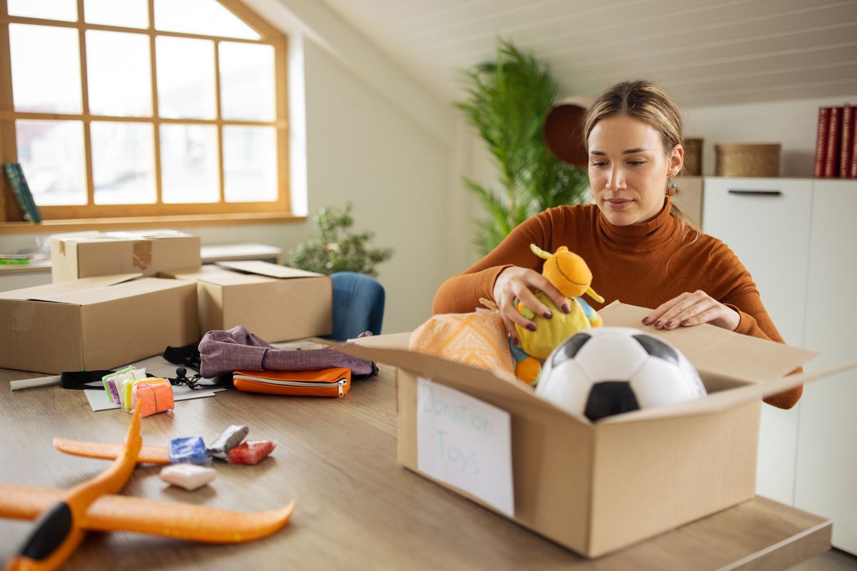 Dedicated Caucasian female volunteer, packing toys for donation into cardboard box