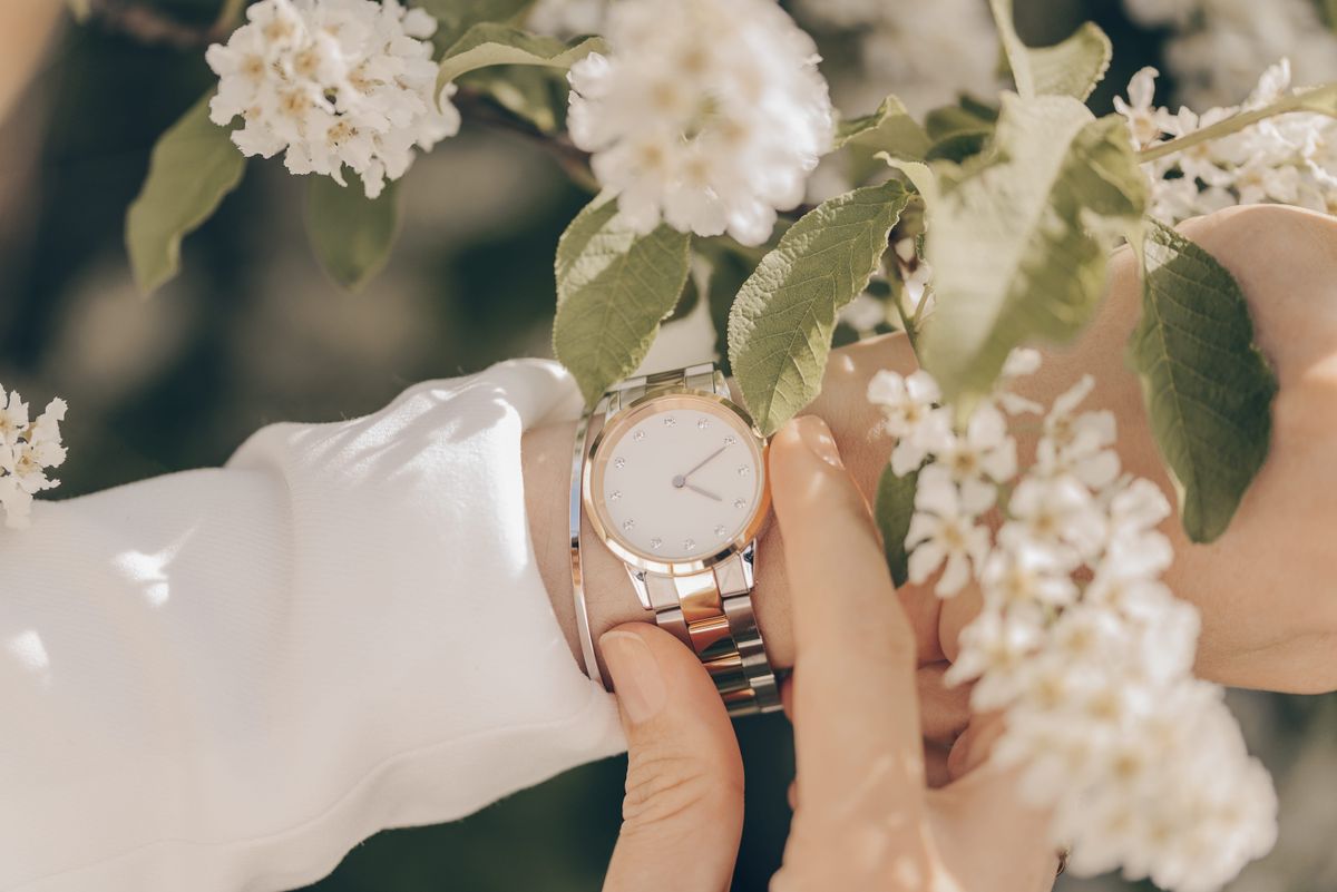 divatos karórák, illusztráció egy női kézen divatos óra tavaszi virágok között
