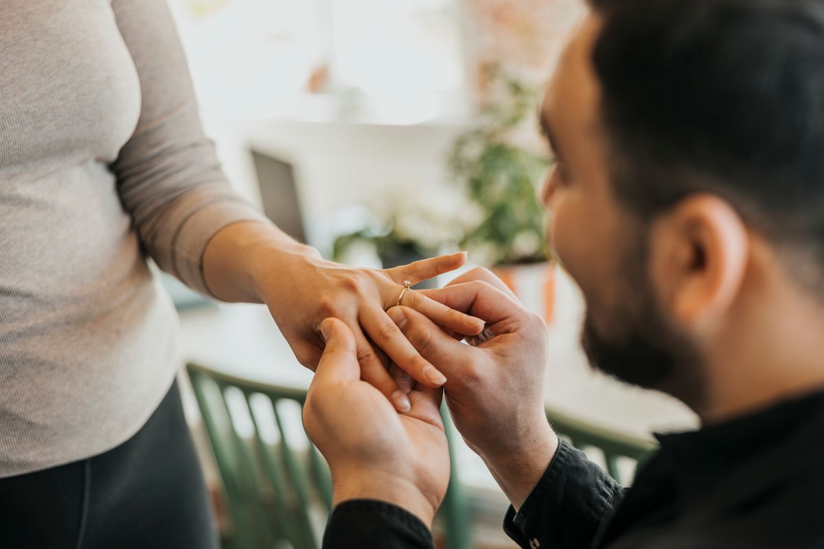 Egy férfi eljegyzési gyűrűt húz a párja kezére.