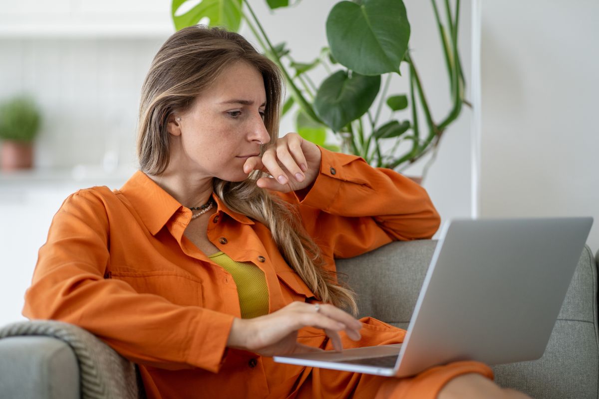 Fiatal nő laptoppal az ölében képes IQ-teszten gondolkodik