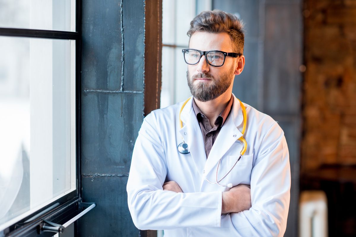 Egy férfi orvos szemüvegben, aki megcsaláson töri a fejét.