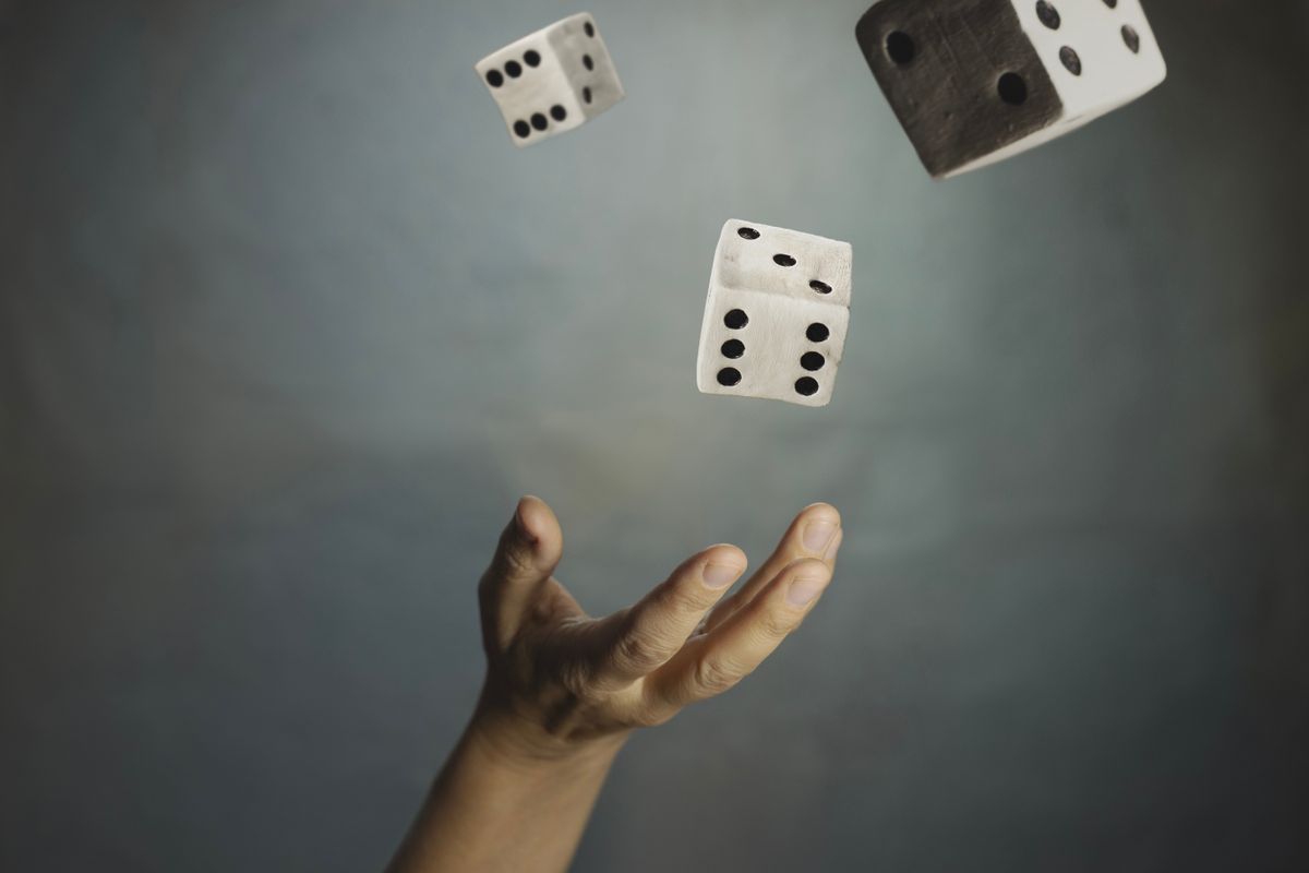 Hand throwing dice into the air, representing the concept of luck, probability, and destiny.