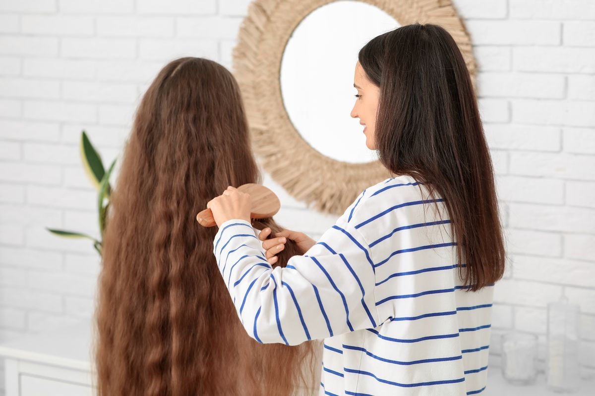 genetikailag barna hajú kislányt fésülő édesanya