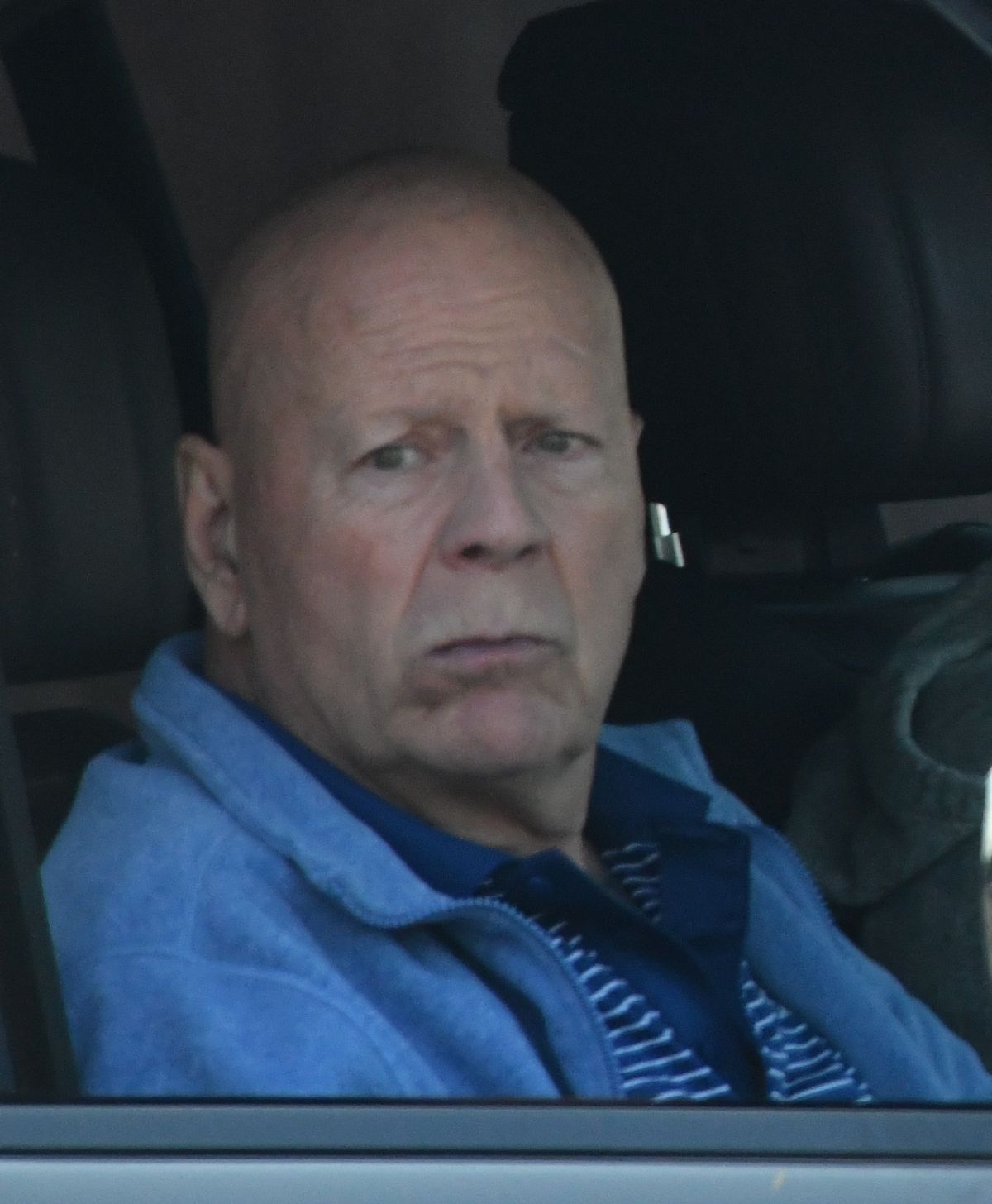 A fotón Bruce Willis látható, ahogy egy autóban ül. 