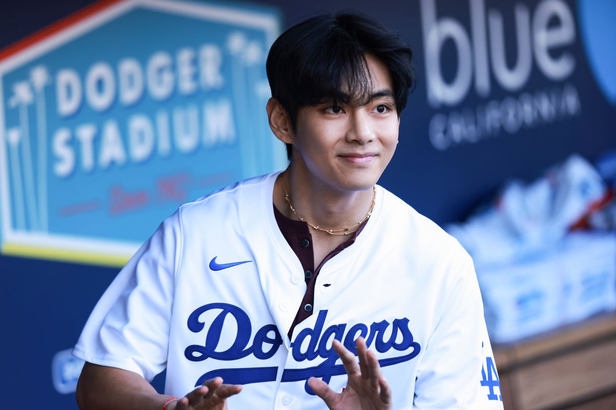 LOS ANGELES, CA - AUGUST 25: BTS singer V looks on from the dugout prior to throwing out the ceremonial first pitch prior to the game between the Cincinnati Reds and the Los Angeles Dodgers at Dodger Stadium on Monday, August 25, 2025 in Los Angeles, California. (Photo by Nicole Vasquez/MLB Photos via Getty Images)