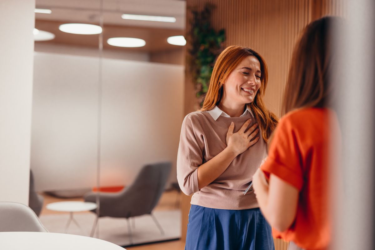 Túlzott kedvességel küzdő nő beszélget és mosolyog. 