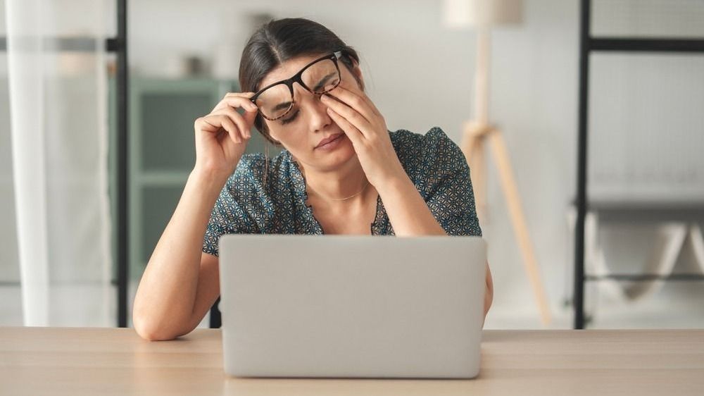 Fiatal nő laptop előtt, szemdörzsölés cikkhez