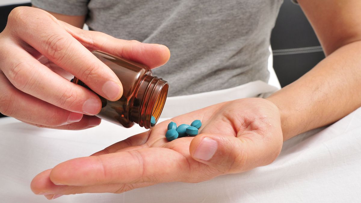 Egy férfi Viagra gyógyszert önt a kezébe. 