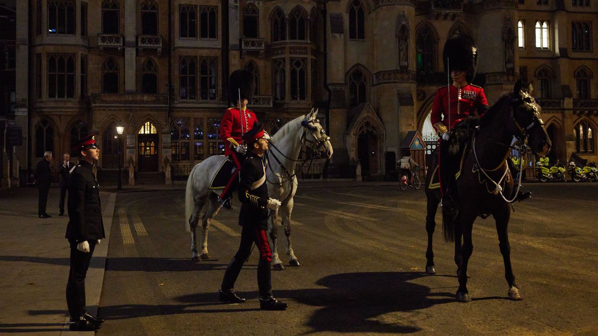 A brit királyi család, és az uralkodó, Károly király védelmét ellátó tisztek állnak a  Windsori kastély bejárata előtt. 