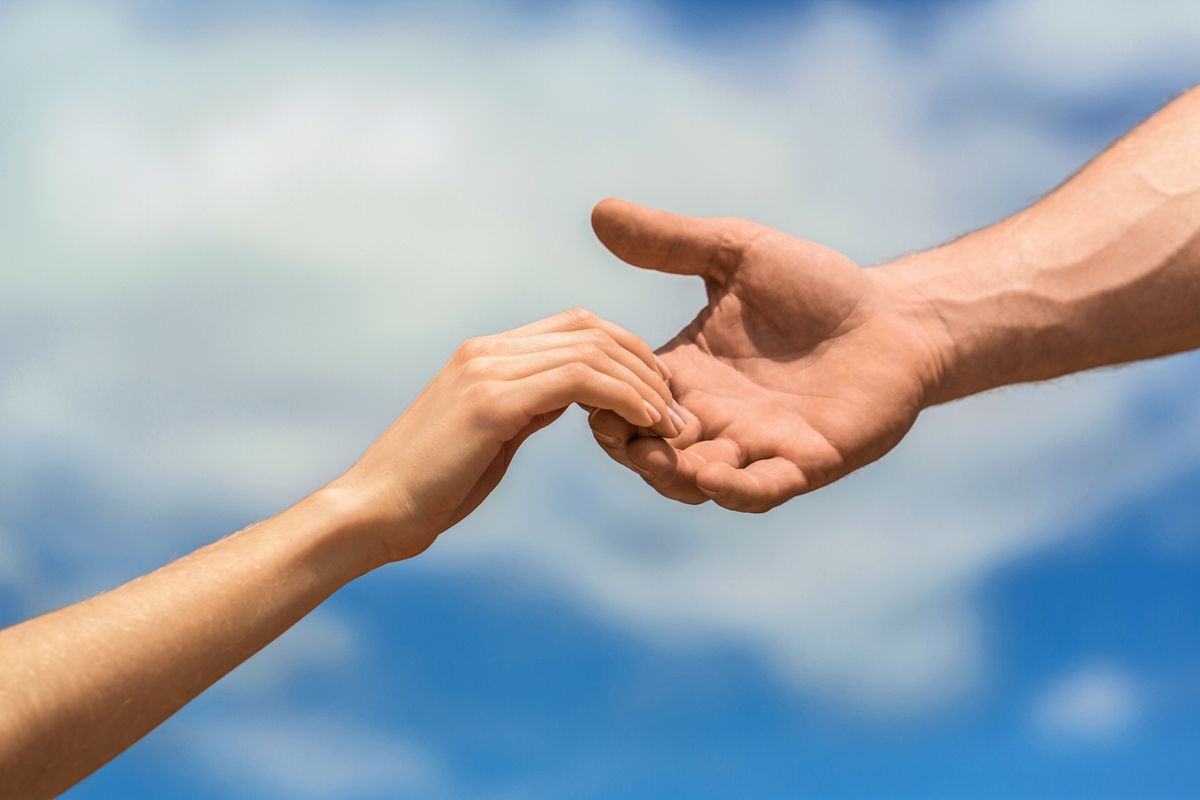 Hands of man and woman on blue sky background. Lending a helping hand. Solidarity, compassion, and charity, rescue. Hands of man and woman reaching to each other, support. Giving a helping hand.