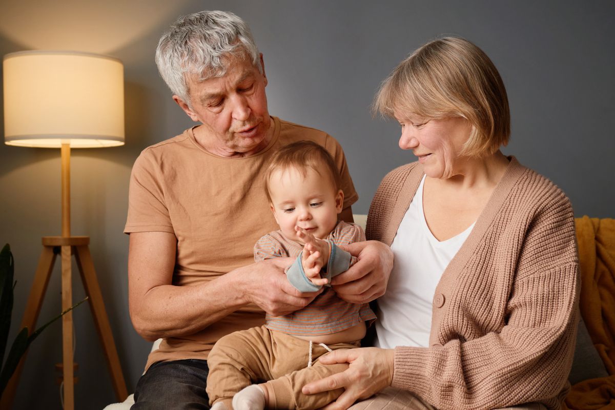 A joyful moment unfolds as grandparents interact with their delighted grandchild in a warm, inviting indoor setting, filled with love and laughter.