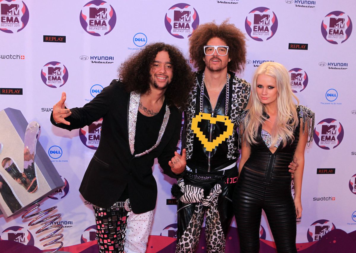 Skyblu (L) and Redfoo (C) of US electro pop band LMFAO pose with British artist Lauren Bennett (L) on the red carpet at the MTV European Music Awards (EMA) at the Odyssey Arena in Belfast, Northern Ireland, on November 6, 2011. AFP PHOTO / PETER MUHLY (Photo by PETER MUHLY / AFP)