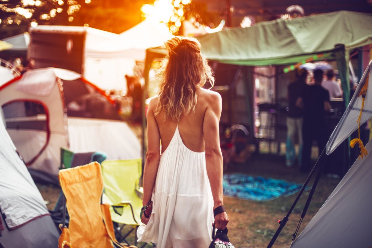 Beautiful young woman walking on festival camping tents for sunset dancig party