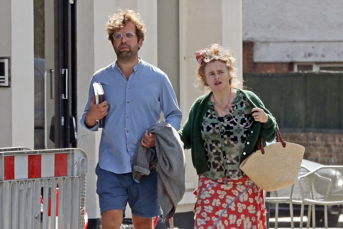 *EXCLUSIVE* London, UNITED KINGDOM Helena Bonham Carter, 58, is spotted linking arms with her boyfriend Rye Dag Holmboe, 36, as they enjoy a dog walk together. Bonham Carter shows off her distinctive sense of style in a green patterned cardigan layered over a floral top, paired with a red floral midi skirt featuring a contrasting light-coloured hem. She completes the look with grey socks and grey lace-up trainers, while carrying a woven straw shoulder bag and wearing sunglasses. Holmboe is seen wearing a light blue button-up shirt with blue shorts and sandals, carrying books under one arm and holding a grey jumper in the other as he walks their dogs. Bonham Carter is also seen wearing a ring on the ring finger of her left hand as the couple stroll together, sparking rumours about a possible engagement. *Pictures Containing Children Please Pixelate Face Prior To Publication*,Image: 1128557348, License: Rights-managed, Restrictions: RIGHTS: WORLDWIDE EXCEPT IN UNITED KINGDOM, Model Release: no , Pictured: Helena Bonham Carter, Rye Dag Holmboe