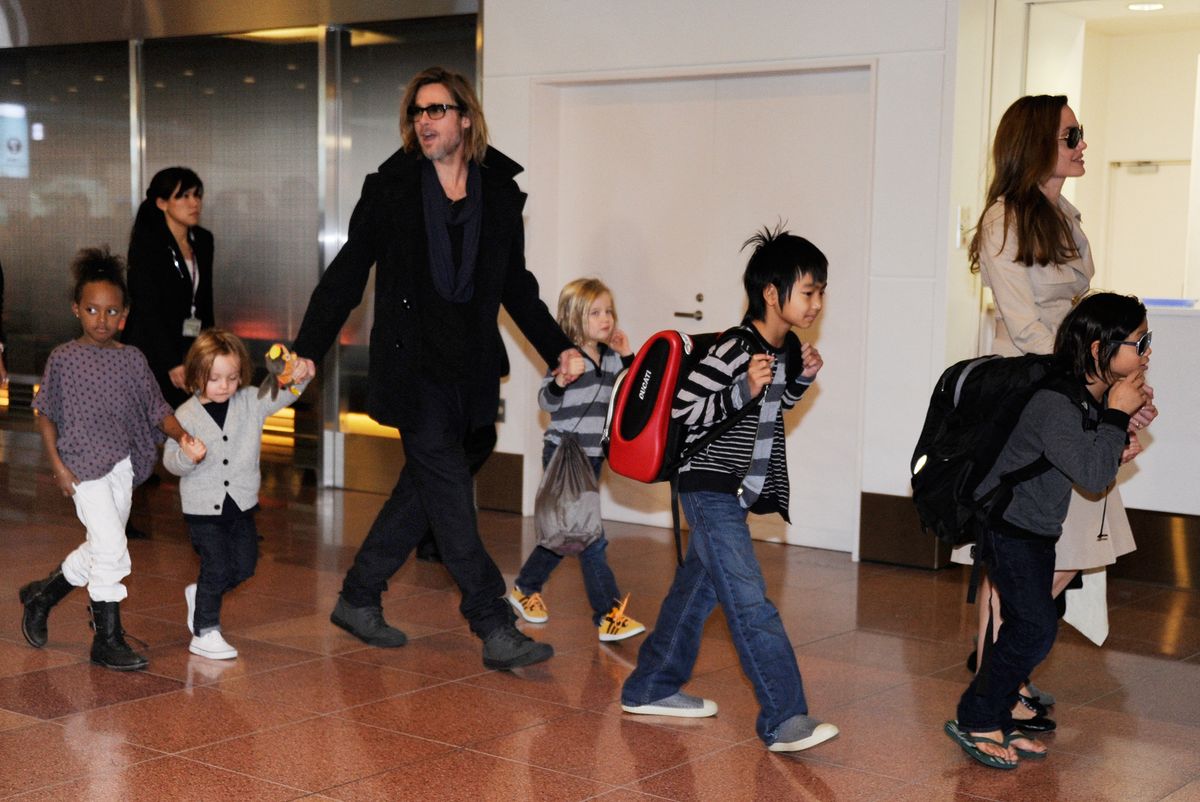 Accompanied by their children, US movie stars Brad Pitt and Angellina Jolie appear before photographers upon their arrival at Haneda Airport in Tokyo on November 8, 2011. Brad Pitt is here for the Japan premiere of his last film 'Moneyball'.   AFP PHOTO/Toru YAMANAKA (Photo by TORU YAMANAKA / AFP)