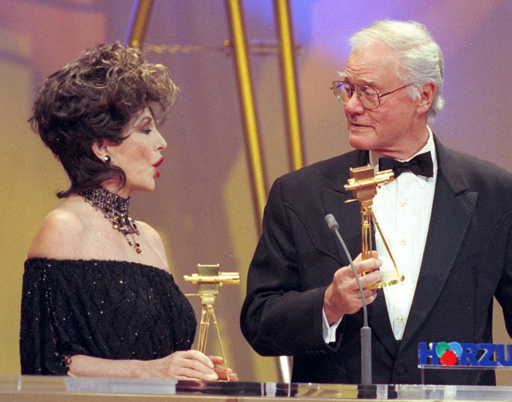 Az amerikai színészek, Joan Collins és Larry Hagman a „Golden Cameras” díjaikat tartják a kezükben a berlini díjátadó ünnepségen, 1999. február 9-én.