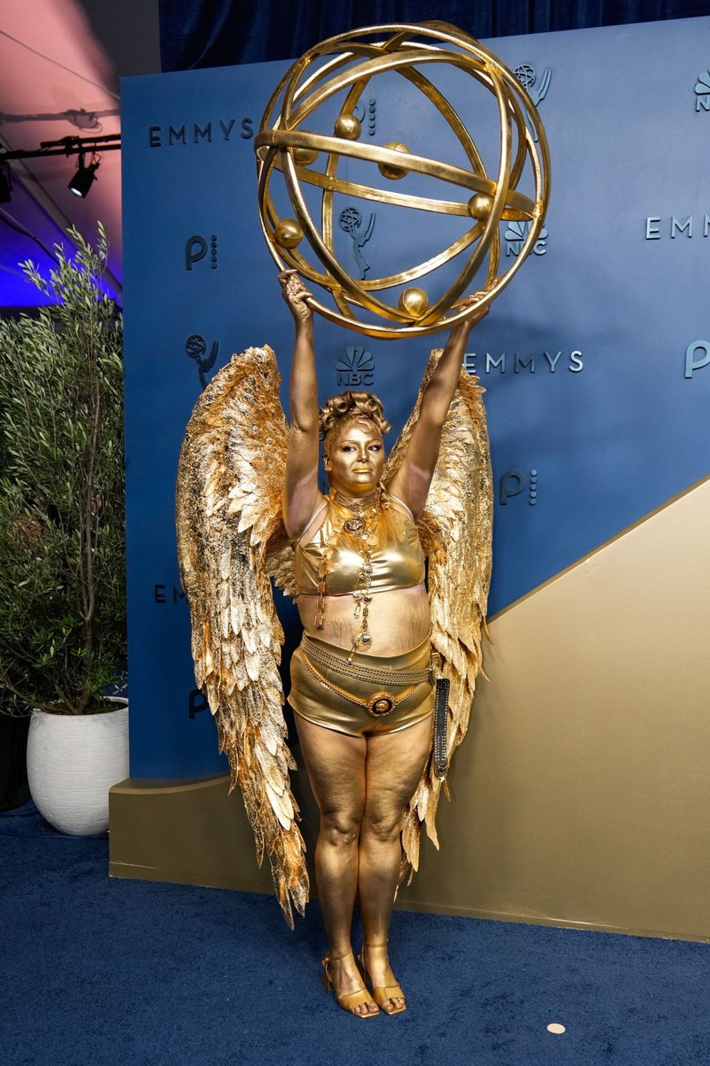 Meg Stalter komikus szó szerint Emmy-díjnak öltözött: testét fémes arany színű testfestékkel festette be, és hatalmas arany szárnyakat viselt. A megjelenést egy pár arany magassarkúval, minirövidnadrággal és nyakpántos, rövid felsővel egészítette ki.