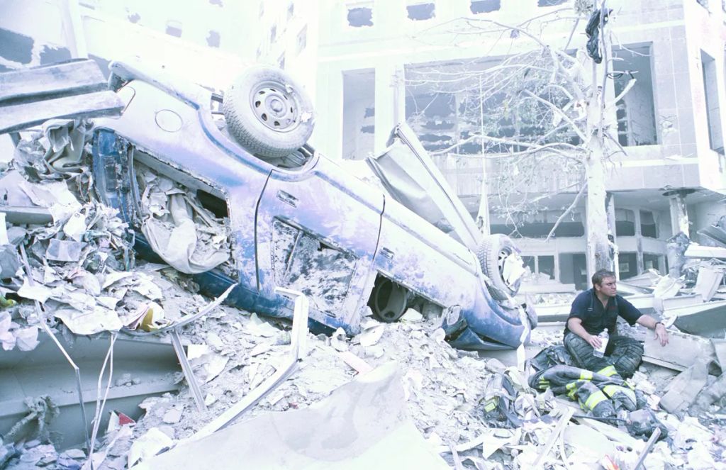 Szeptember 11-én délután egy magányos NYFD-tűzoltó pihen egy jármű mellett, amelyet a World Trade Center elleni 9/11-es támadás után a leomló tornyok ereje sodort el.