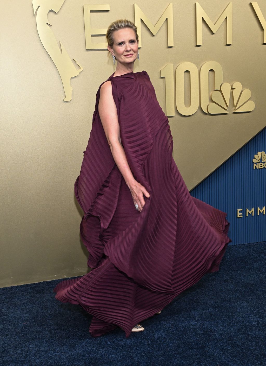 Cynthia Nixon egy bordó színű, ráncos ruhában jelent meg az Emmy-gála vörös szőnyegén. A ruha olyan bő és hatalmas volt, hogy teljesen elnyelte a színésznőt. A szetthez egy Manolo Blahnik magas sarkúvat választott.
