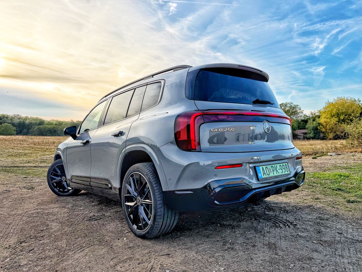 Szürke Mercedes-Benz GLB 250+ EQ AMG Line hátulról, füves területen parkolva.
