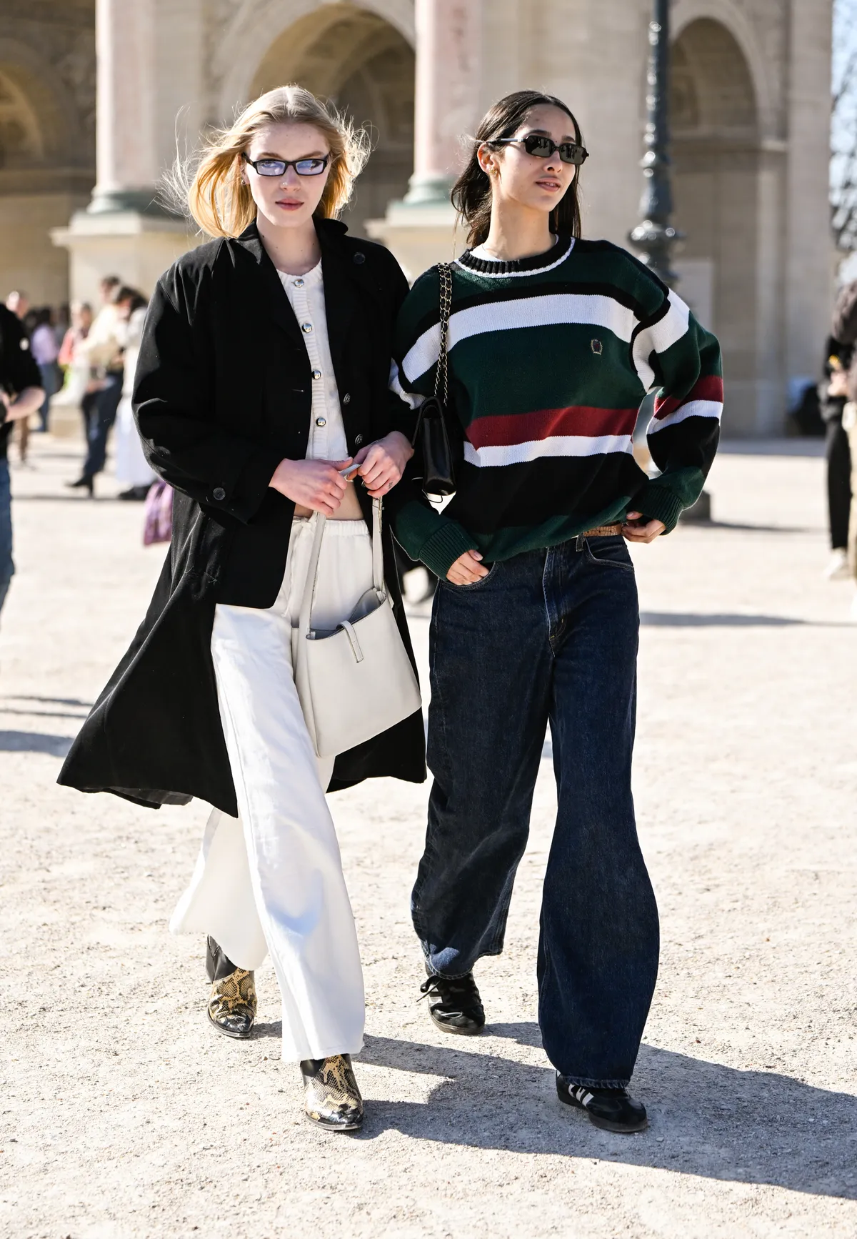 PARIS, FRANCE - MARCH 05: Models Colin Jones seen wearing a black coat, white top, white pants, snakeskin boots and white bag and Yasmin Wijnaldum seen wearing a striped sweater, blue jeans and black bag and sunglasses outside the Casablanca show during the Womenswear Fall/Winter 2025/2026 as part of Paris Fashion Week on March 05, 2025 in Paris, France. (Photo by Daniel Zuchnik/Getty Images)